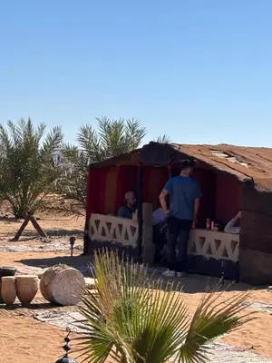 a man standing outside of a small house in the desert at Camp Desert Sky in Merzouga