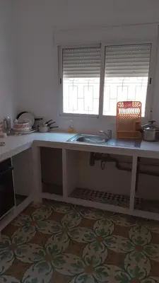 a kitchen counter with a sink and two windows at chez zoubida in Meknès