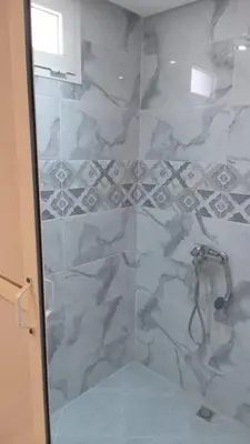 a bathroom with a shower with a glass door at chez zoubida in Meknès