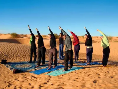 a group of people doing yoga in the desert at Camp Local Family in Mhamid