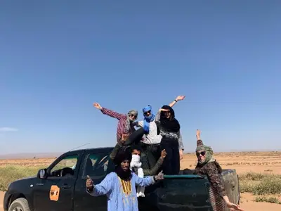 a group of people standing in the back of a truck at Camp Local Family in Mhamid