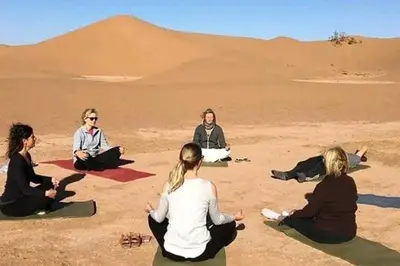 a group of women sitting in the desert at Camp Local Family in Mhamid
