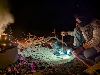 a person sitting in front of a fire with candles at Camp Local Family in Mhamid