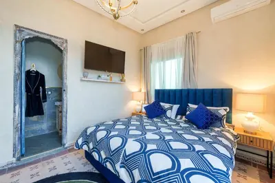 a bedroom with a blue and white bed and a mirror at Villa les Oliviers avec piscine privée & jardin - Atlas view in Marrakech