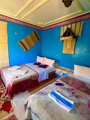 two beds in a room with blue walls at Maison d'hôte Riad Todra in Tinerhir