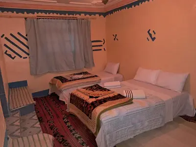 two beds in a room with a window at Maison d'hôte Riad Todra in Tinerhir