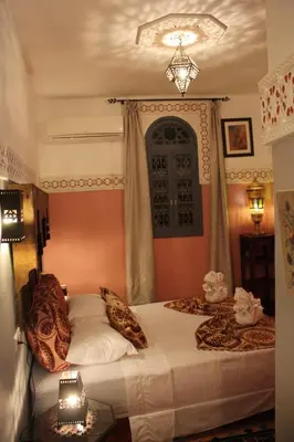 a bedroom with a bed and a chandelier at Ryad Meknassia in Meknès