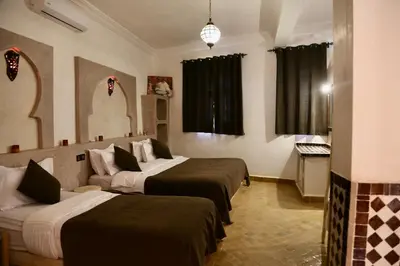 a hotel room with three beds and a mirror at Merzouga Riad Desert Man in Merzouga