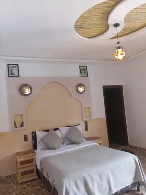 a bedroom with a large bed and a ceiling at Merzouga Riad Desert Man in Merzouga
