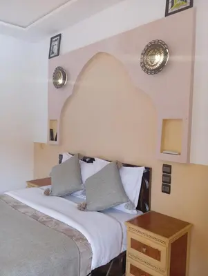a bedroom with a bed and a wooden table at Merzouga Riad Desert Man in Merzouga