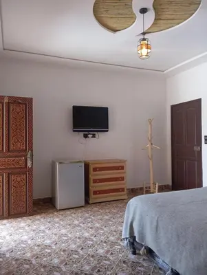 a bedroom with a bed and a flat screen tv at Merzouga Riad Desert Man in Merzouga