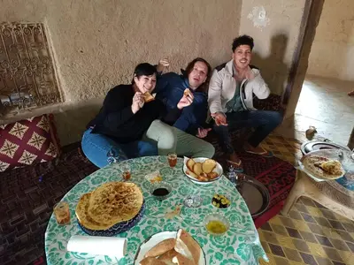a group of people sitting around a table eating food at Guest House Nomad Life in Merzouga