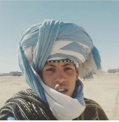 a man wearing a turban on his head in the desert at Guest House Nomad Life in Merzouga