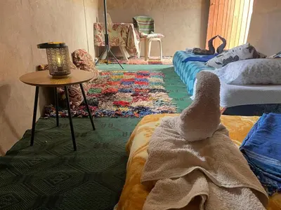 a room with two beds and a table with a towel at Guest House Nomad Life in Merzouga