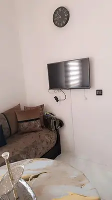 a living room with a couch and a clock on the wall at Appartement Basatine in Fès