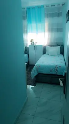 a bedroom with a bed and a blue curtain at Appartement Basatine in Fès