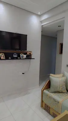 a living room with a couch and a tv on a wall at Appartement Basatine in Fès