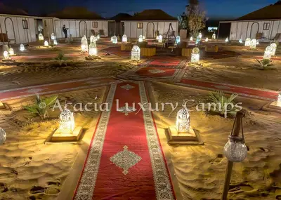 a courtyard lit up at night with lights at Merzouga Desert Camps in Merzouga