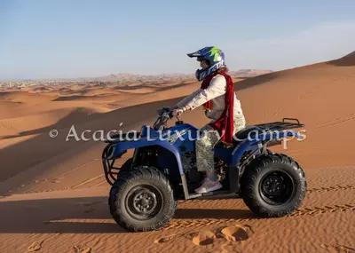 a man riding a wheeler in the desert at Merzouga Desert Camps in Merzouga