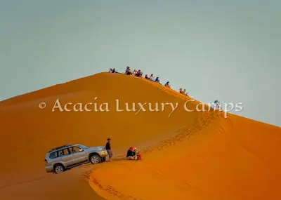 a group of people standing on top of a sand dune at Merzouga Desert Camps in Merzouga