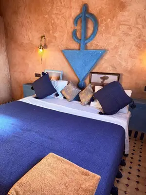 a bedroom with a large bed with a blue blanket at Riad camels house in Merzouga
