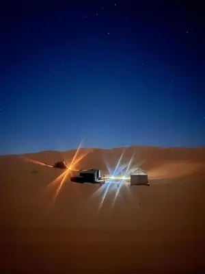 a truck driving through the desert at night at Riad camels house in Merzouga