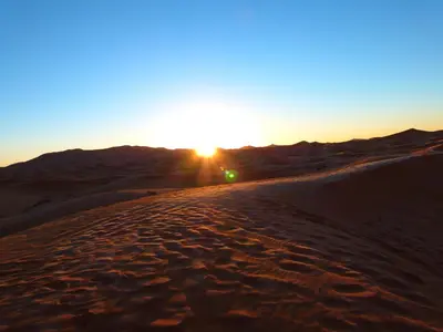 a sunset on the sand in the desert at Riad camels house in Merzouga