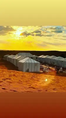 a group of domes in a field with the sunset at Idir Luxury Camp in Merzouga