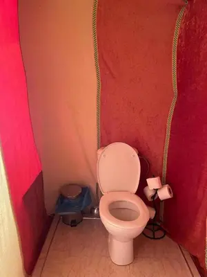 a small bathroom with a toilet in a red wall at Idir Luxury Camp in Merzouga