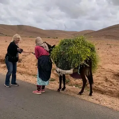 two women standing on the side of a road next to a horse at GITE ROURAL TATIOUINE Midelt in Tattiouine