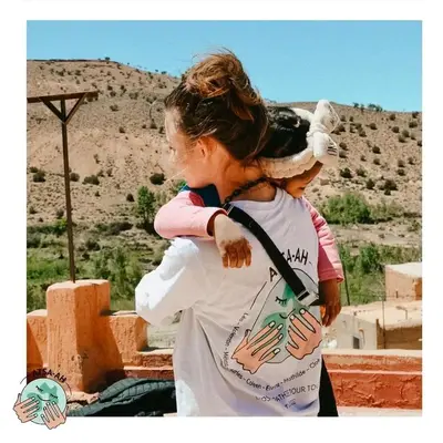 a woman carrying a child on her back at GITE ROURAL TATIOUINE Midelt in Tattiouine