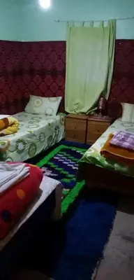 a bedroom with two beds and a rug on the floor at GITE ROURAL TATIOUINE Midelt in Tattiouine