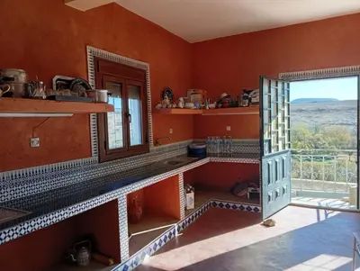 a kitchen with orange walls and a door with a window at Auberge Assays in Taliouine