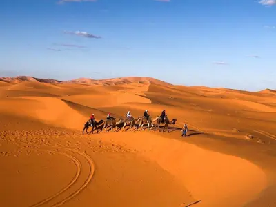 a group of people riding horses in the desert at Royal Sands Luxury Camp in Merzouga