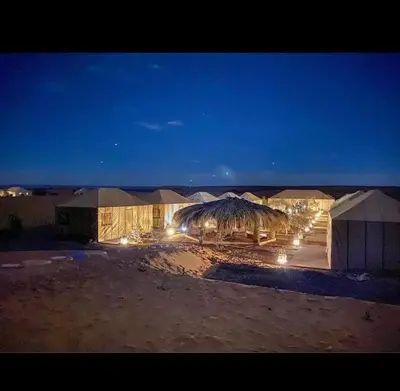 a group of tents in the desert at night at Royal Sands Luxury Camp in Merzouga