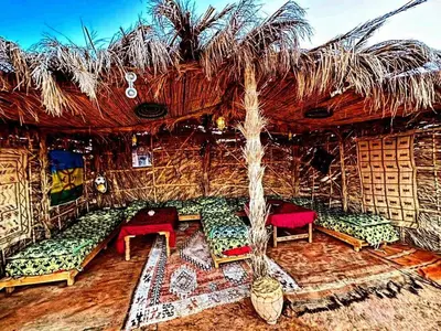 a room with couches and a thatch roof at Royal Sands Luxury Camp in Merzouga
