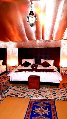 a bedroom with a large bed with a wooden headboard at Royal Sands Luxury Camp in Merzouga