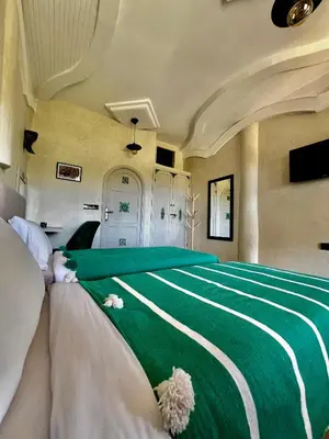 a bed in a room with green and white sheets at Jnane Ayam Atlas in Ourika