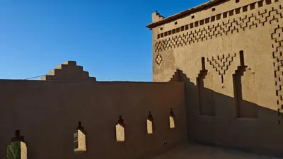 a shadow of a building with a clock on it at kasba Harmony in Oulad Saïd