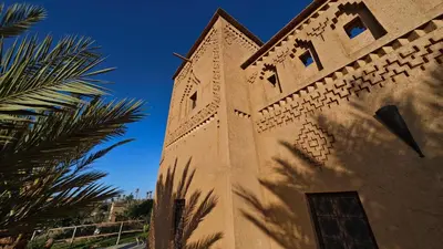 a tower of a building with a palm tree next to it at kasba Harmony in Oulad Saïd