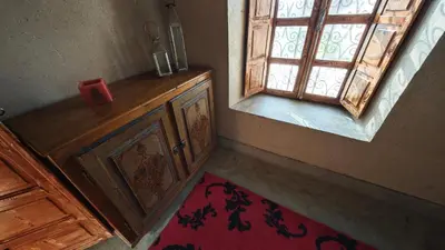 an empty room with a window and a red rug at kasba Harmony in Oulad Saïd