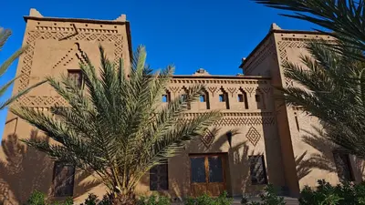 a building with a palm tree in front of it at kasba Harmony in Oulad Saïd