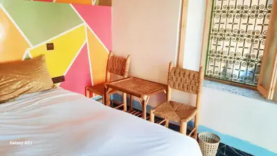 a bedroom with a bed and two chairs at Studio avec cuisine - kitchen in Tinerhir