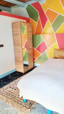 a bedroom with a colorful wall with a bed and cabinets at Studio avec cuisine - kitchen in Tinerhir