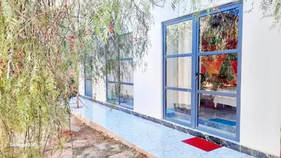 a window in a white house with trees at Studio avec cuisine - kitchen in Tinerhir