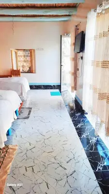 a room with two beds and a tiled floor at Studio avec cuisine - kitchen in Tinerhir