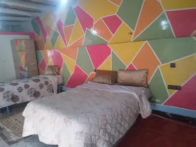a room with a bed and a colorful wall at Studio avec cuisine - kitchen in Tinerhir