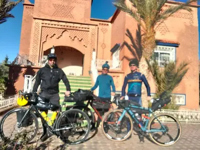 three men standing next to their bikes in front of a building at chez l'habitant de compagne in Tamensourt