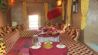 a living room with couches and a table with teaitures at Kasbah Maison D’hôte Lalla Zahra in Aït Baha