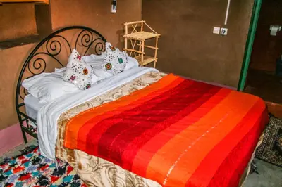 a bed with a colorful blanket and pillows on it at Kasbah Maison D’hôte Lalla Zahra in Aït Baha
